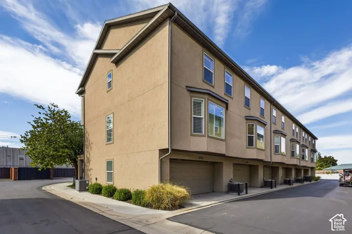 Multi-level stucco exterior featuring multiple bay windows, individual garage doors, and integrated landscaping
