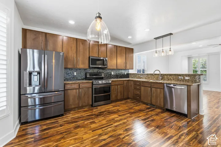 Full kitchen featuring wood-finish flooring, stainless steel appliances, upper and lower cabinetry, a mosaic tile backsplash, and recessed lighting