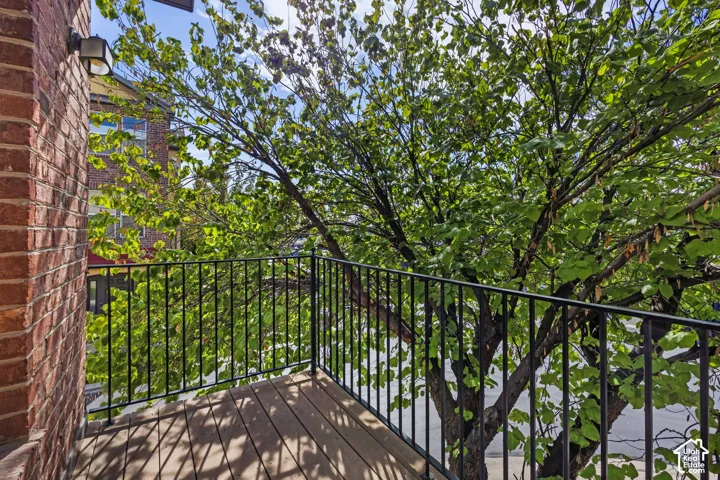Private balcony featuring wood-finish decking and black wrought iron railing