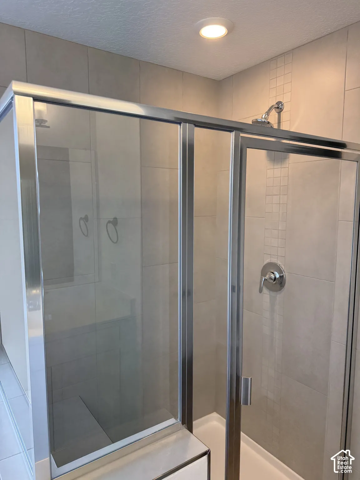 Glass-enclosed shower with polished chrome fixtures, integrated bench, and tiled walls featuring a decorative inset