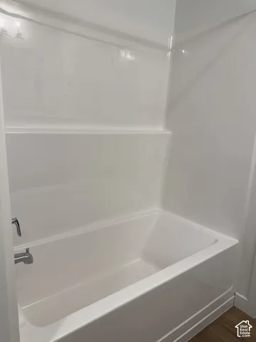 White bath and shower combination with integrated shelving