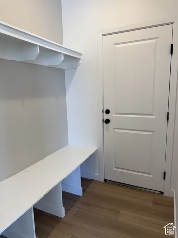 Built-in bench with integrated shelving, paneled door with black hardware, and wood-finish flooring