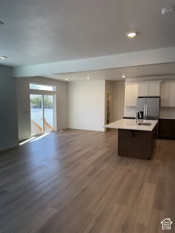 Open-concept living area with wood-finish flooring, recessed lighting, and a sliding glass door