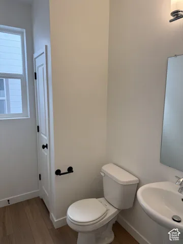 Pedestal sink with chrome faucet, wall-mounted mirror, and wood-finish flooring