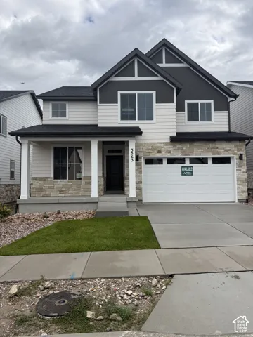 Contemporary two-story exterior with a covered porch, stone facade accents, dark siding, and a two-car garage