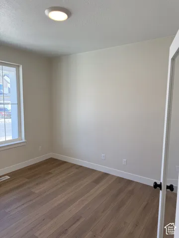 Wood-finish flooring, white trim, recessed lighting, and a white interior door with black hardware