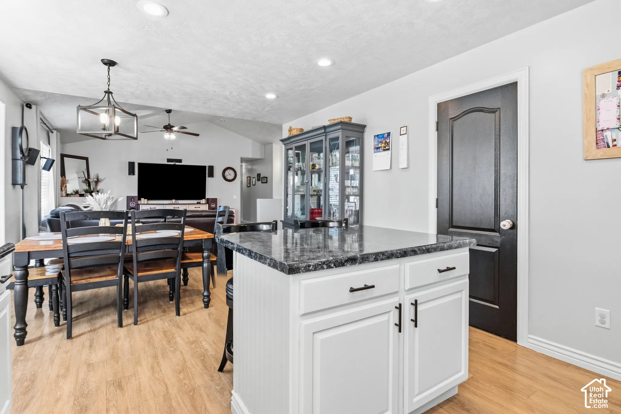 Kitchen island with white cabinetry, dark countertop, and black hardware