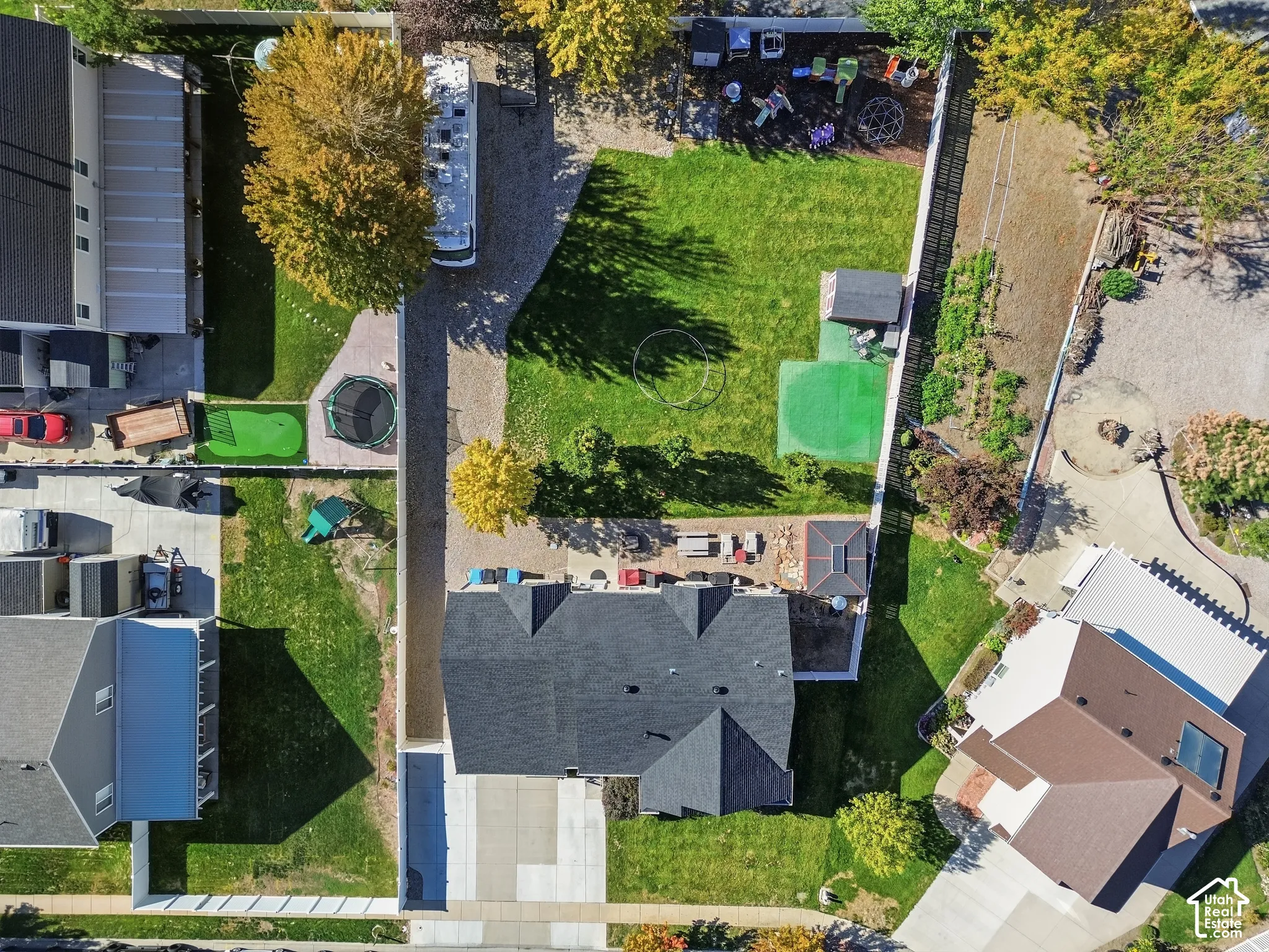 Expansive green lawn, gravel driveway, privacy fencing, and mature trees