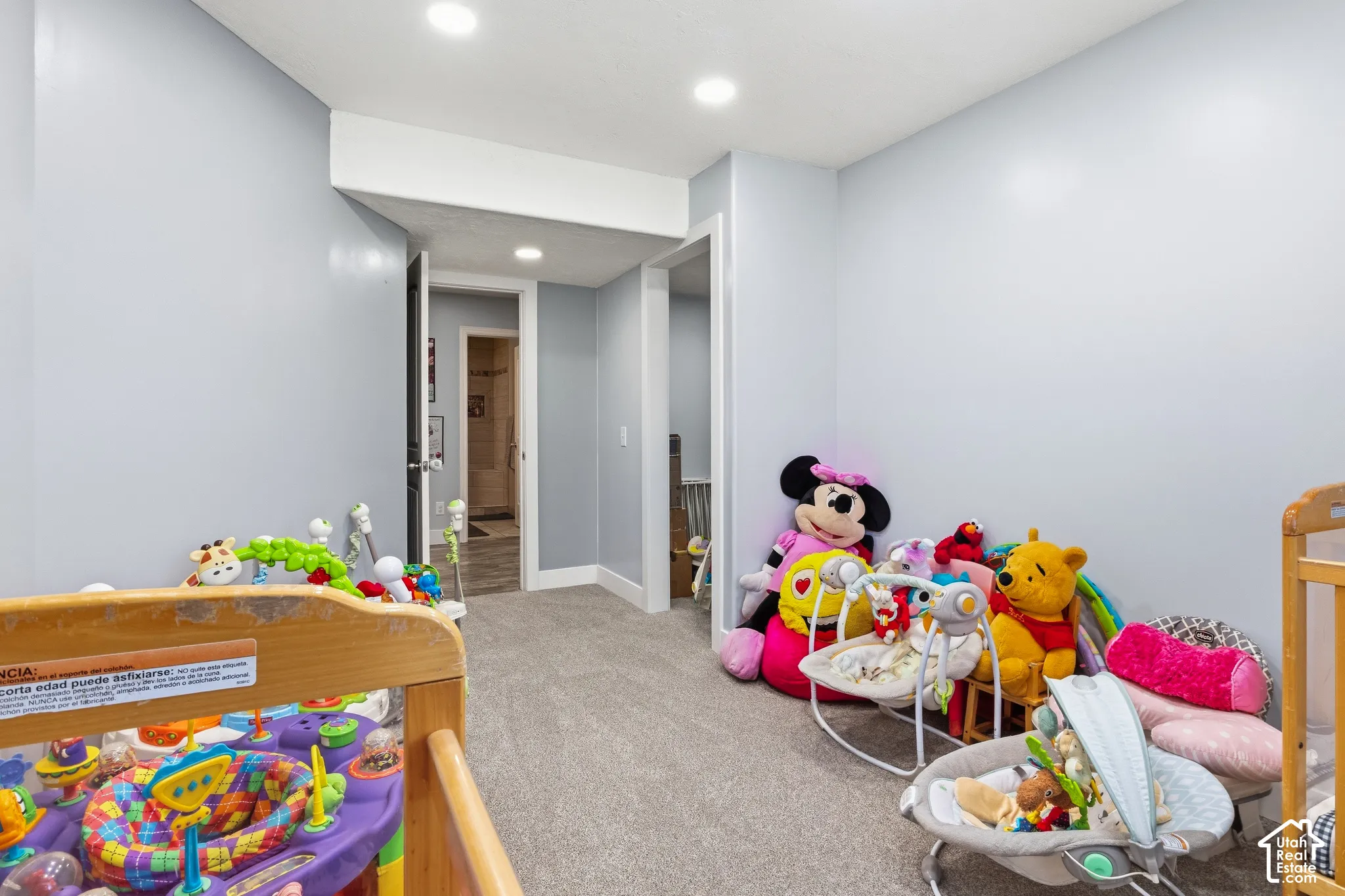 Recessed lighting illuminates the carpeted room with light gray walls and white trim