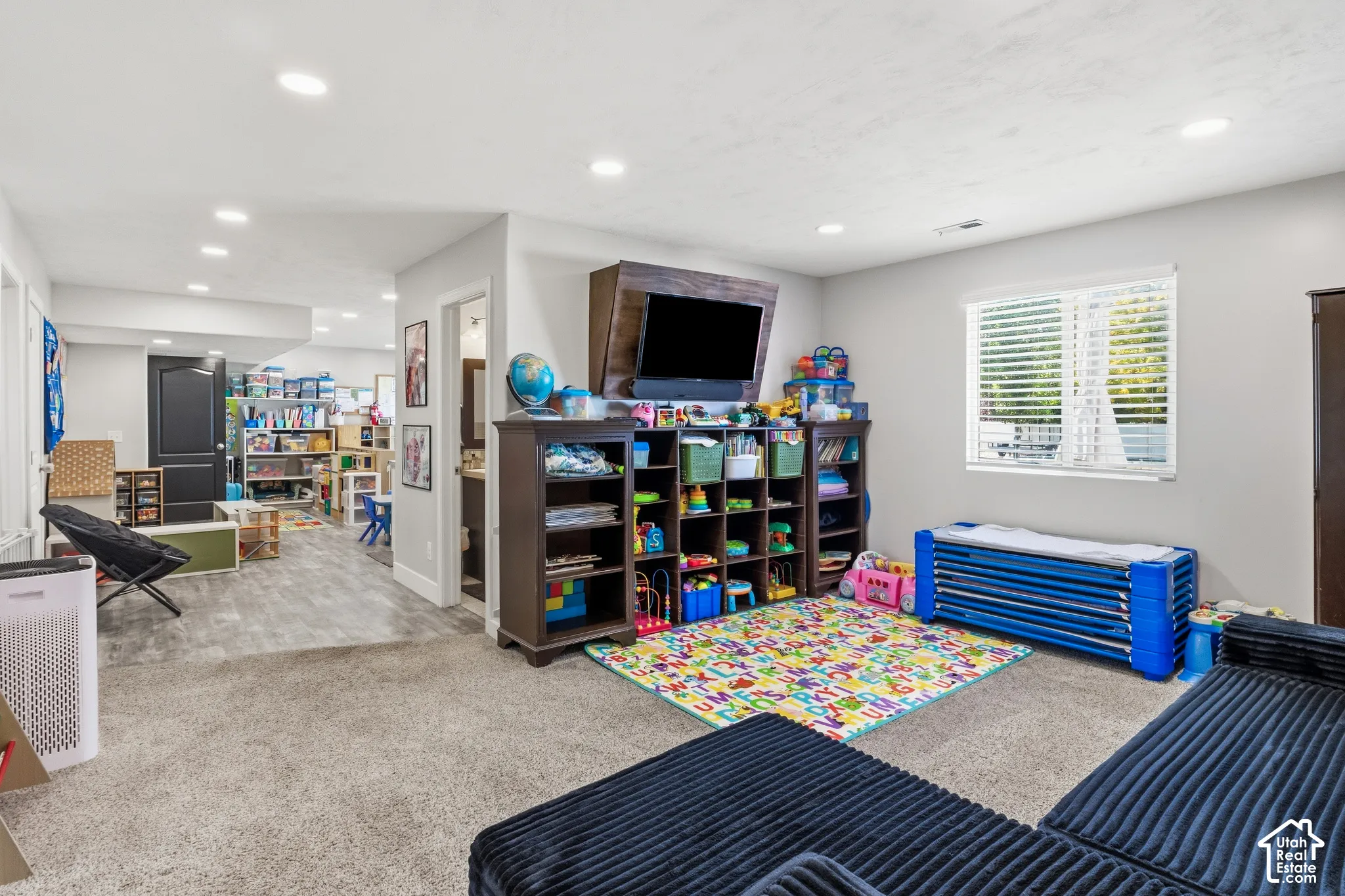 Recessed lighting, wood-finish flooring, and a large window with horizontal blinds