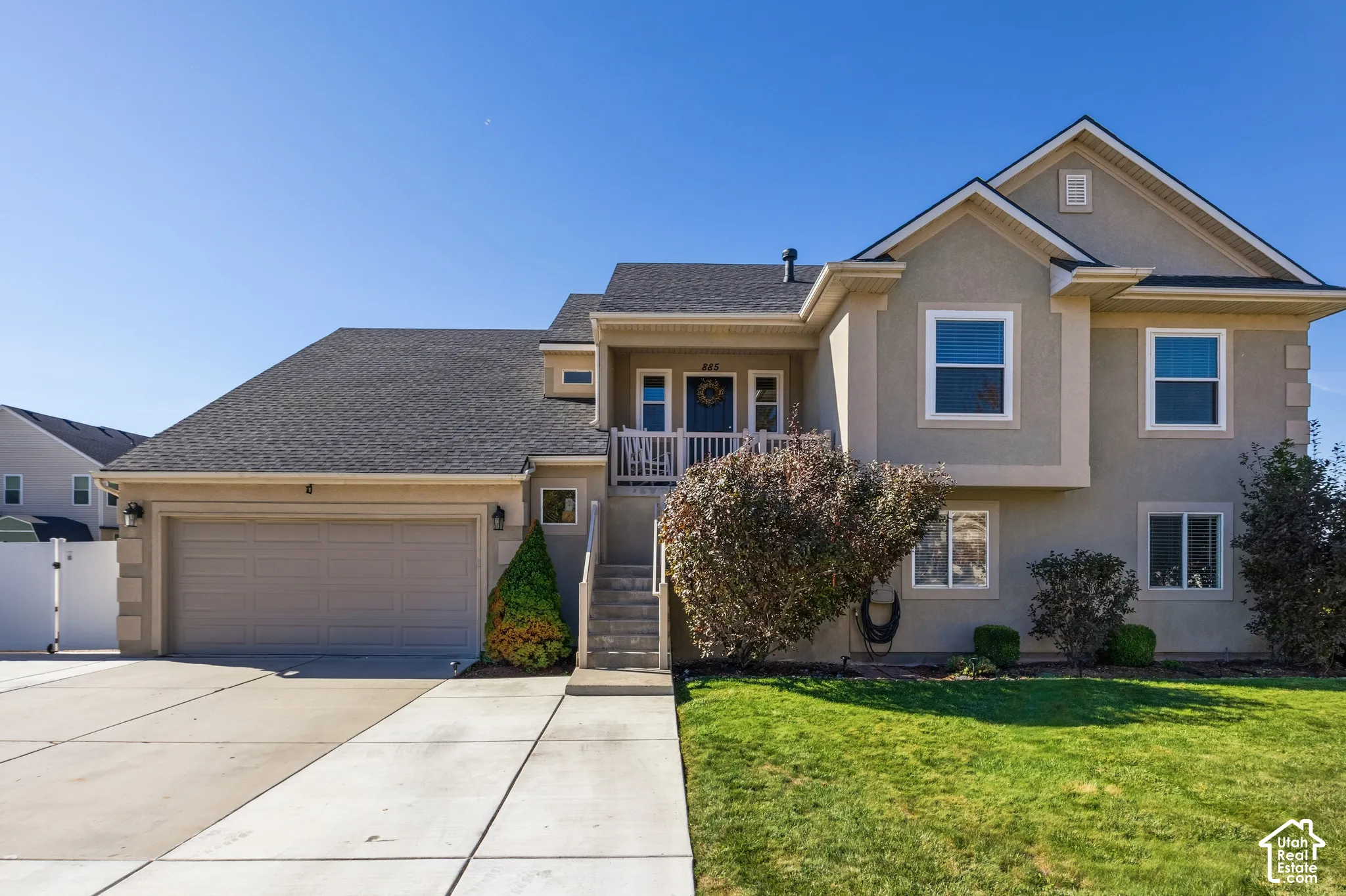 Stucco exterior featuring multiple windows and a gray asphalt shingle roof
