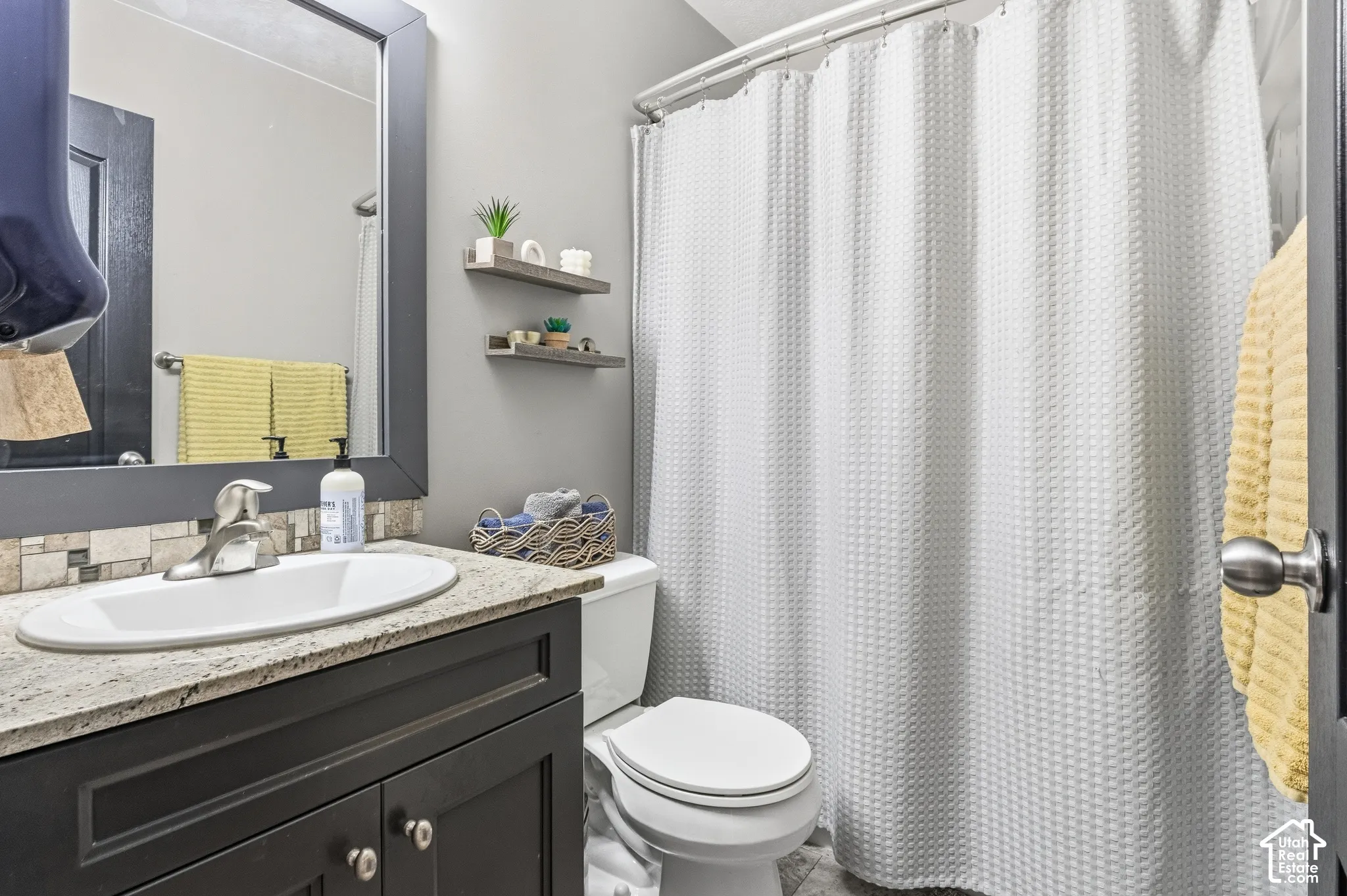 Vanity with a light-colored countertop, undermount sink, and mosaic tile backsplash