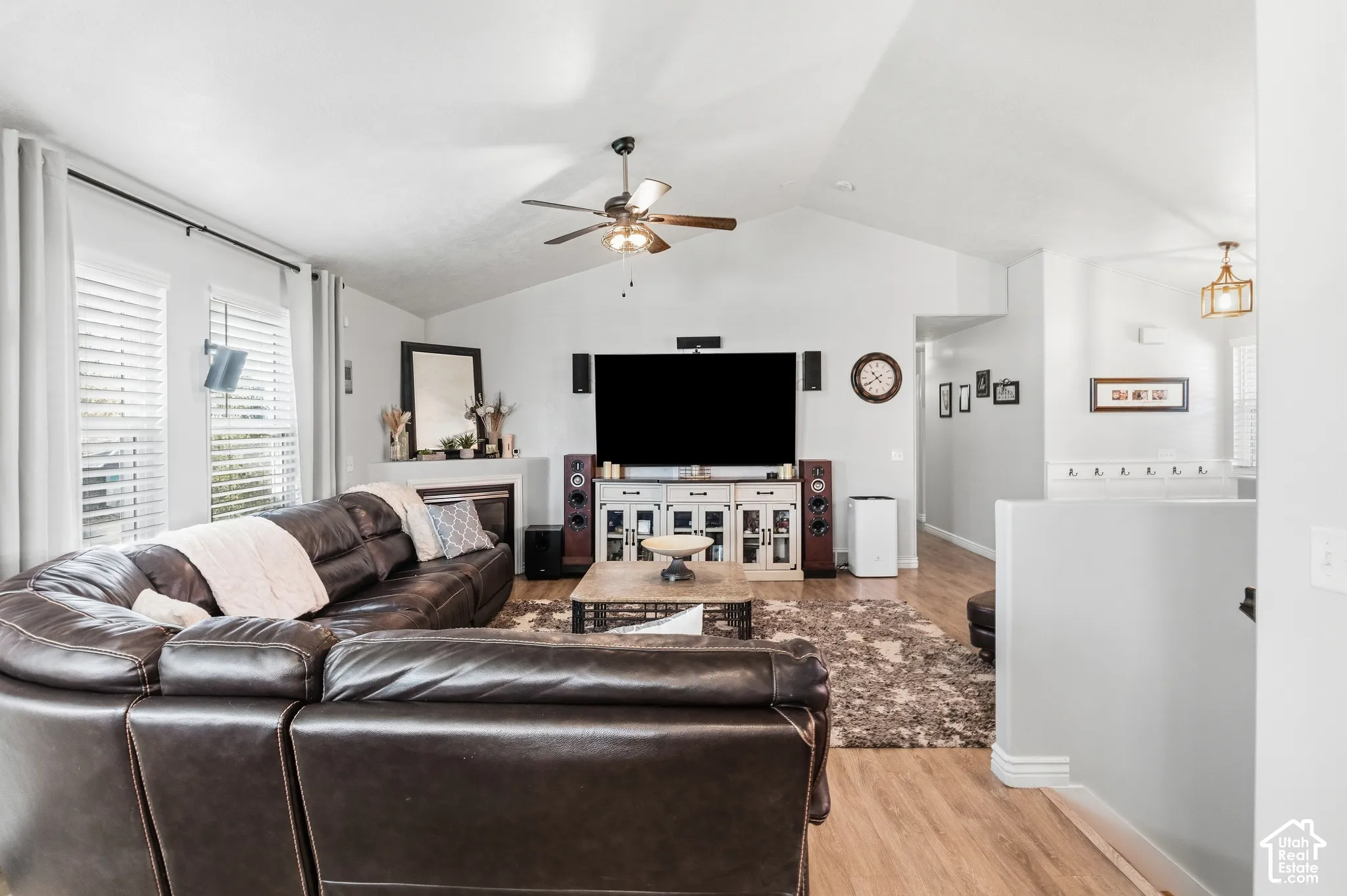 Vaulted ceiling, wood-finish flooring, fireplace, ceiling fan, and window blinds