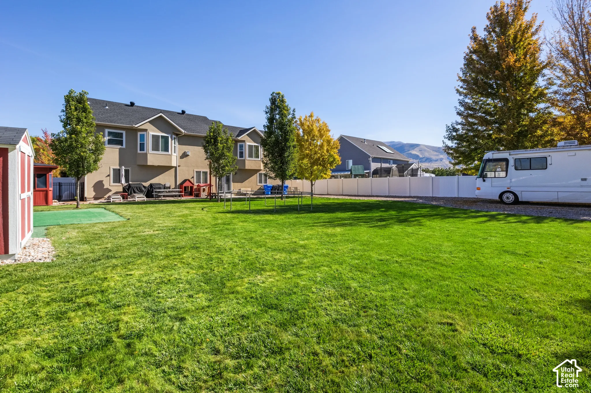 Expansive rear yard featuring a large lawn, mature trees, and a detached storage shed