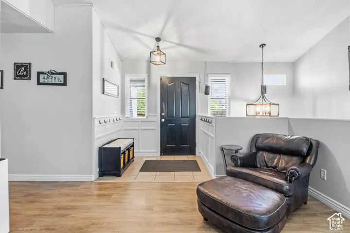 Entryway featuring a dark paneled door, two decorative light fixtures, wood-finish flooring, and wainscoting