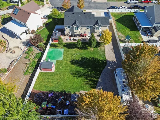 Expansive fenced backyard featuring a grassy lawn, mature trees, a storage shed, and a dedicated gravel area