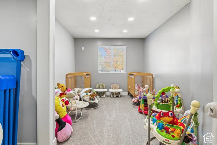 Carpeted room with recessed lighting and a window featuring blinds