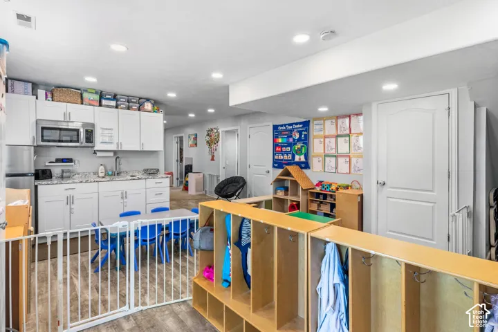 Kitchenette featuring white cabinetry, stainless steel appliances, granite-style countertops, and a stainless steel sink