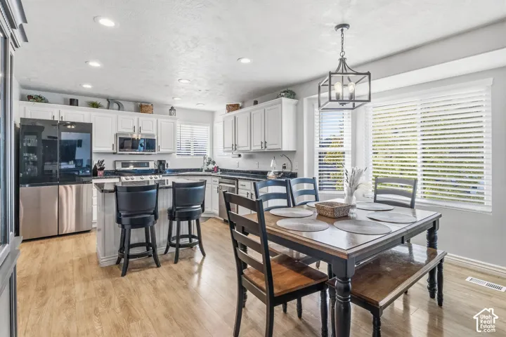 Wood-finish flooring throughout, white cabinetry, dark countertops, built-in stainless steel appliances, and a built-in kitchen island