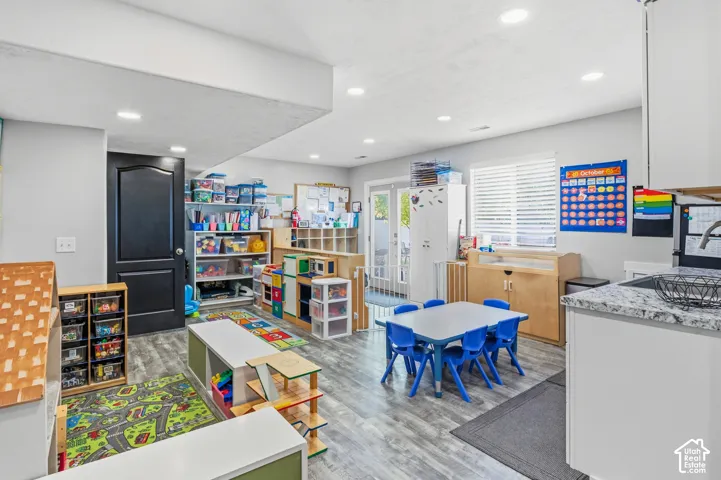 Recessed lighting, wood-finish flooring, white cabinets, light-toned countertop, and a window with blinds