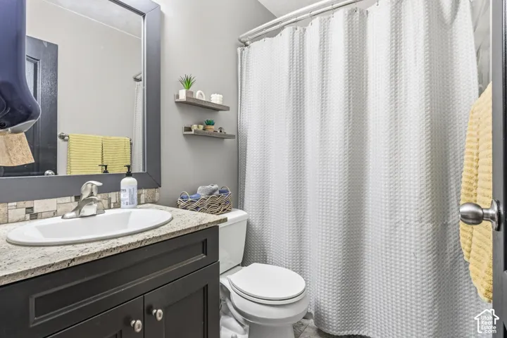 Vanity with a light-colored countertop, undermount sink, and mosaic tile backsplash