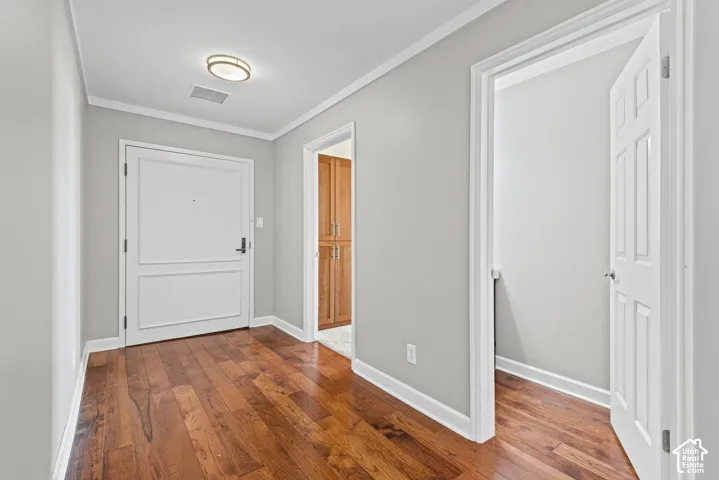 Hardwood-finish flooring, white panel doors, overhead flush-mount lighting, and crown molding