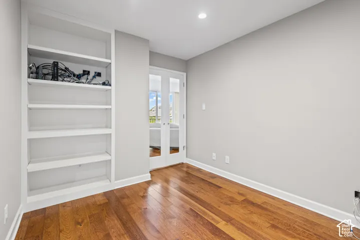 Built-in shelving, hardwood flooring, recessed lighting, and French doors