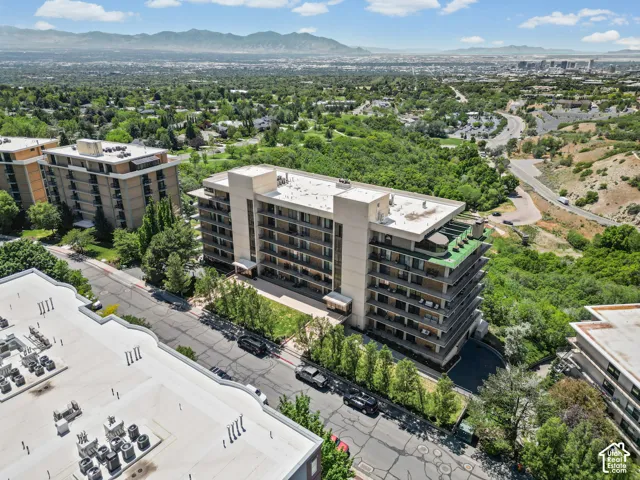 Modern mid-rise residential building featuring clean architectural lines, multiple levels with expansive windows, and green rooftop amenities