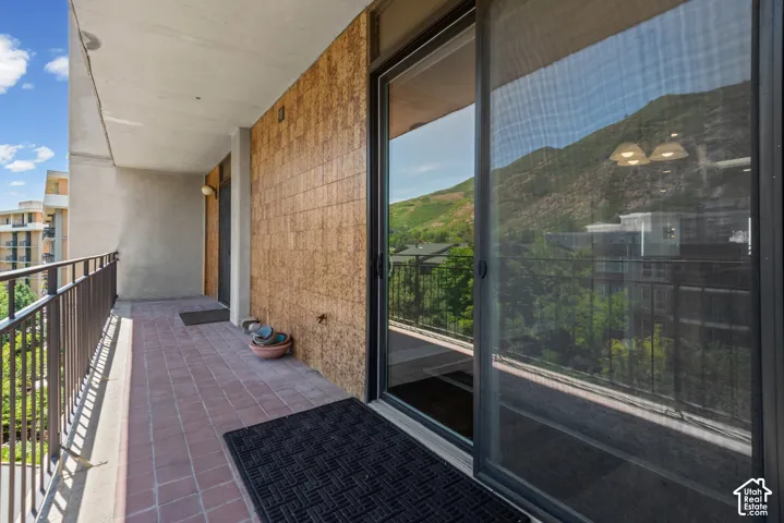 Balcony featuring brick-laid flooring, a metal railing, and a sliding glass door