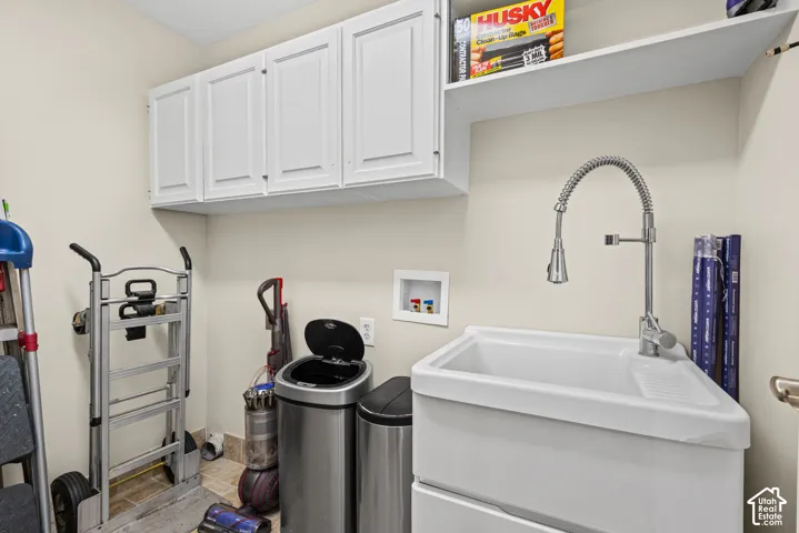 White shaker-style cabinetry with chrome hardware, an open shelving unit, a large utility sink, and a chrome gooseneck faucet