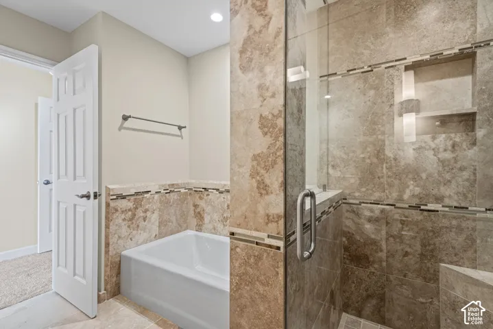 Full tile surround bathtub and shower with glass enclosure, recessed shower niche, and tile flooring