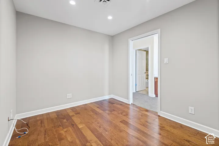 Recessed lighting, wood-finish flooring, light gray wall color, white trim, and a white interior door
