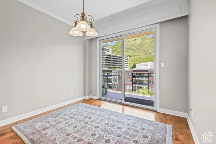 Warm wood-finish flooring, crown molding, and a brass-finish chandelier