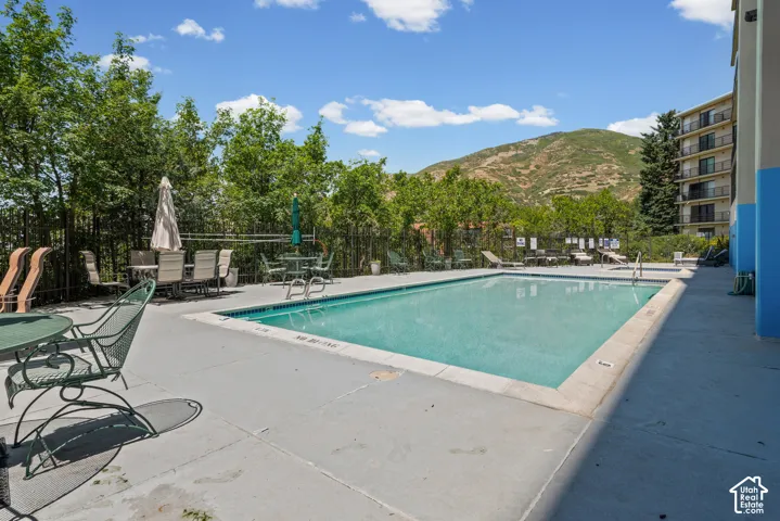 Outdoor swimming pool with a concrete deck, surrounded by mature trees and a distant mountain backdrop