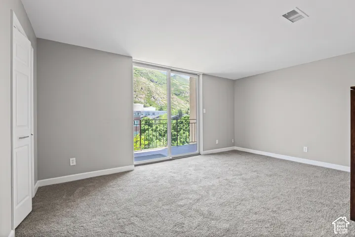 Gray carpeted flooring with light gray walls, a balcony, and a white paneled door
