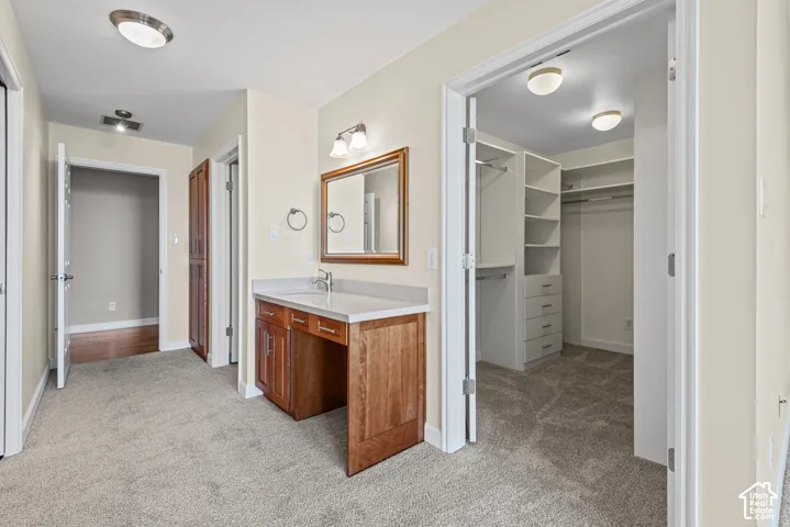Vanity with wood-finish cabinetry and a light-toned countertop, accompanied by a built-in closet system with shelving and drawers