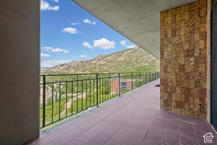Expansive balcony featuring a mountain backdrop, black metal railing, tiled flooring, and textured wall paneling