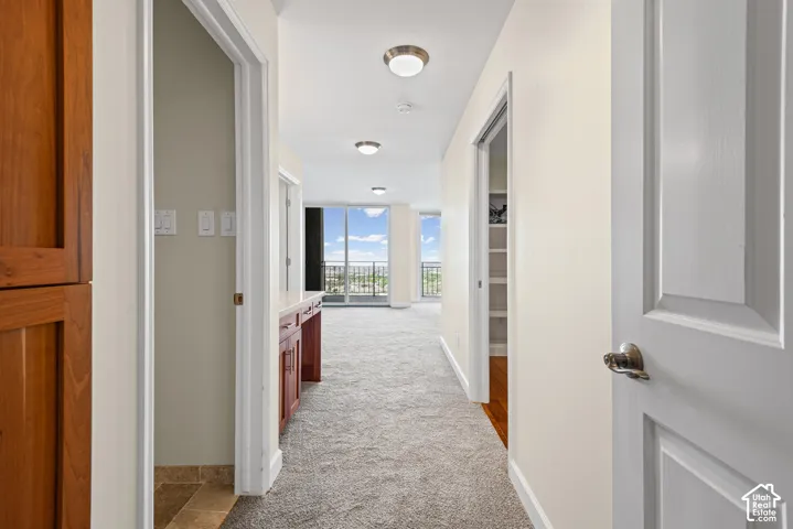 Hallway with recessed lighting, integrated wood-finish cabinetry, built-in shelving, and large windows providing ample natural light