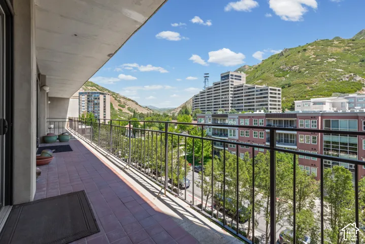 Expansive balcony featuring brick-patterned tile flooring and a decorative metal railing
