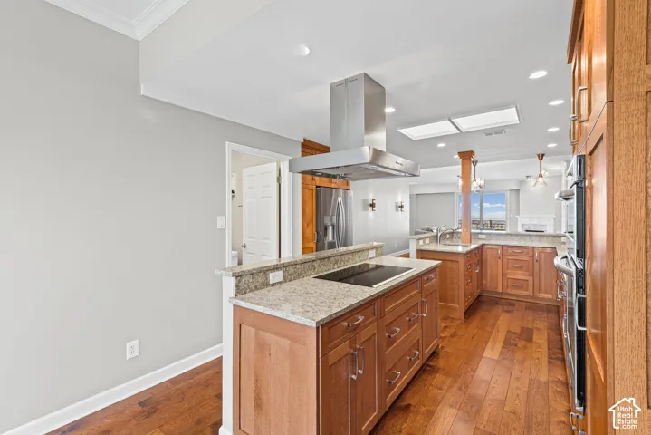 Kitchen featuring wood-finish flooring, granite countertops, wood cabinetry, and stainless steel appliances