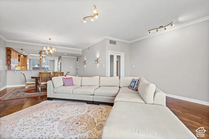 Spacious open-concept living area showcasing a generous sectional arrangement, wood-finish flooring throughout, and abundant natural light from multiple ceiling fixtures