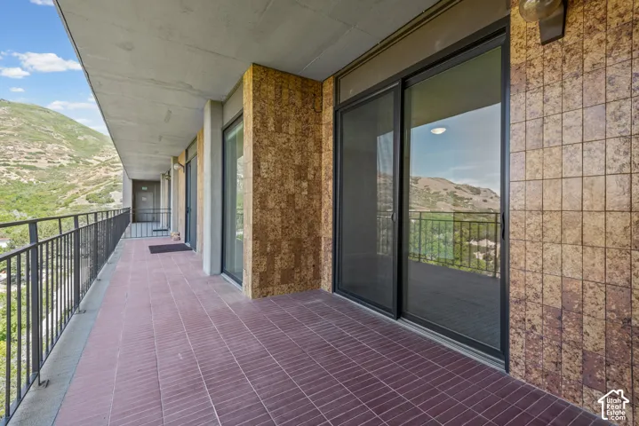 Expansive balcony featuring a tiled floor, dark metal railings, and sliding glass doors
