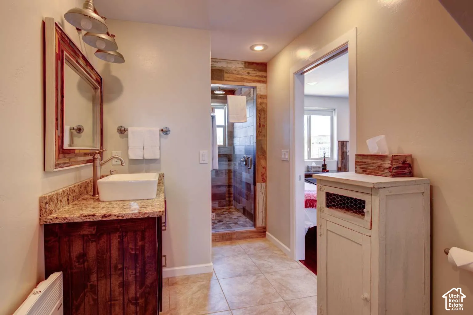 Bathroom featuring a vessel sink, wood-finish vanity, stone countertop, and a shower with wood-panel accents