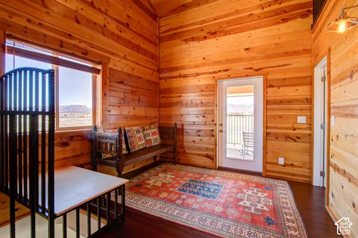 Wood-paneled walls and ceilings, dark wood-finish flooring, and a glass-paneled door opening to an exterior balcony