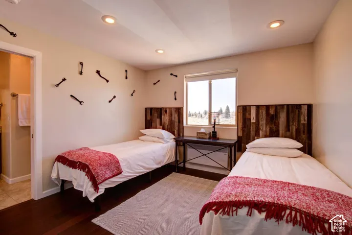 Recessed lighting illuminates the room, featuring wood-finish flooring and a window with a natural landscape