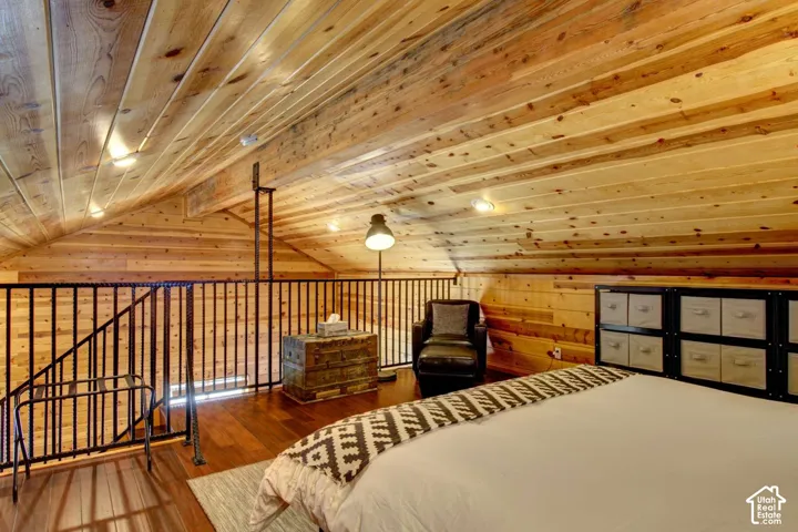 Vaulted wood-paneled ceiling, wood-finish flooring, metal railing, recessed lighting, and a built-in storage unit