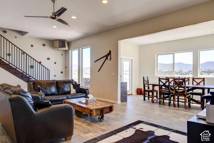 Recessed lighting, ceiling fan, wood-finish flooring, staircase with metal railing, multiple windows