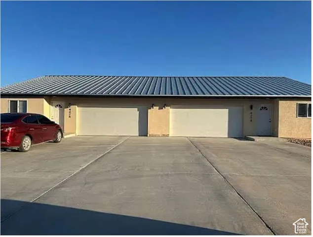 Stucco exterior with a metal roof and concrete driveway