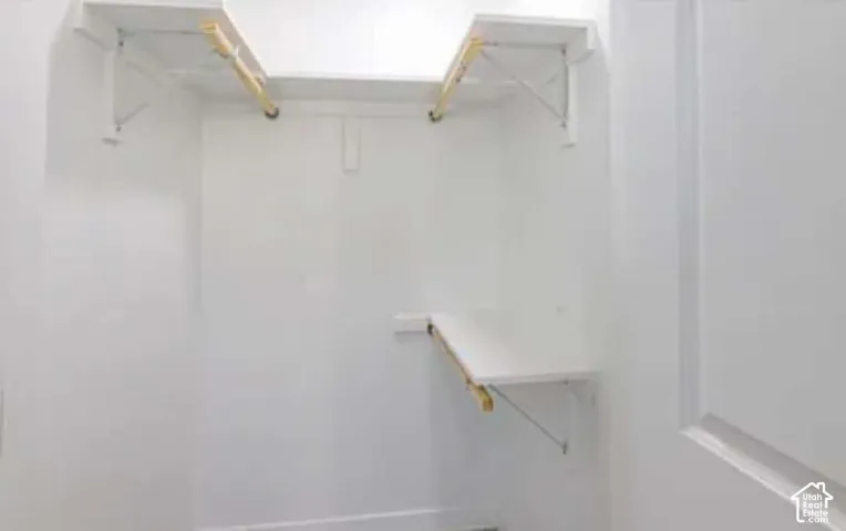 White-painted closet featuring multiple shelves and clothing rods