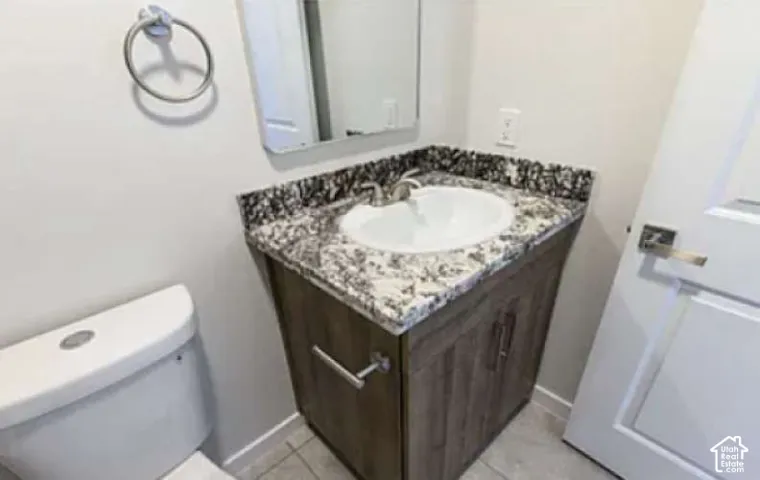 Vanity with a granite countertop, undermount sink, and wood-finish cabinetry